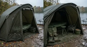 An extended carp fishing bivvy overwrap showing the additional porch storage space containing muddy waders, wellies, an angling stool, and a bait bucket next to a bedchair.