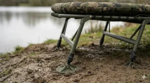 Side profile of a wide boy bedchair featuring one-touch adjustable legs and mud feet for stability on soft bankside terrain.