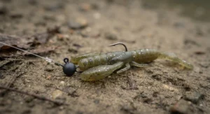 Ned rig soft plastic lure fitted with a micro jig weight resting on a riverbed.